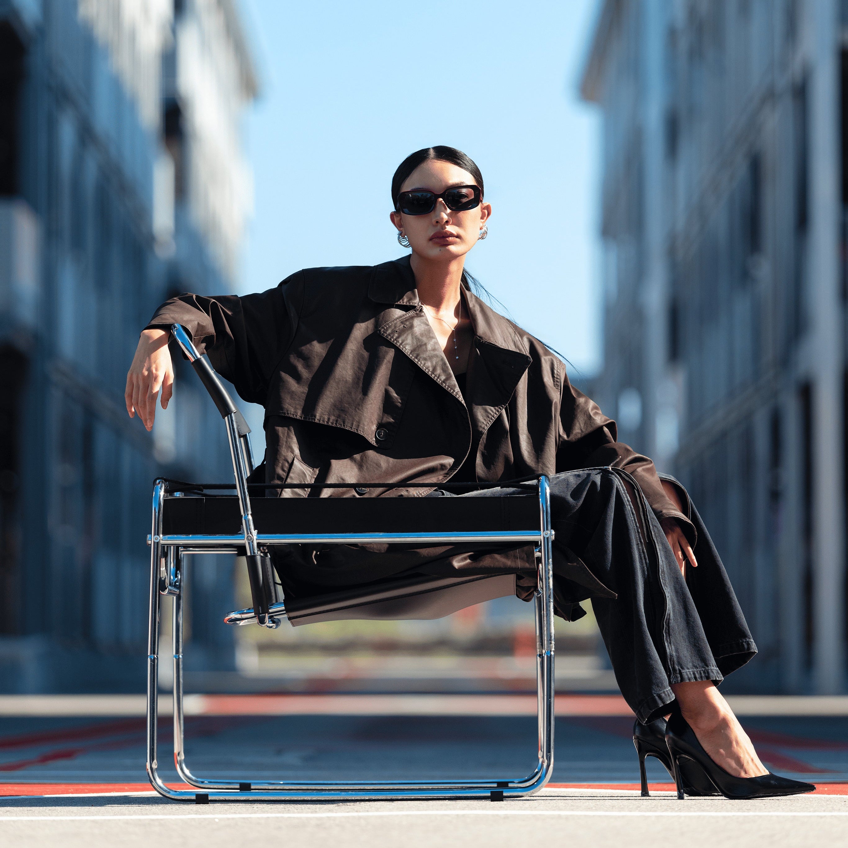 Person sitting on a chair in an urban setting with buildings in the background