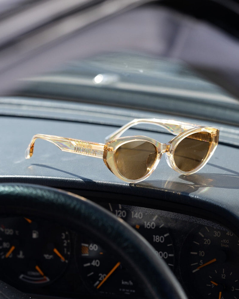 Gold sunglasses on a car dashboard with visible speedometer