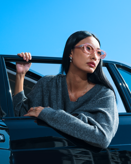 Woman standing next to a black car against a blue sky