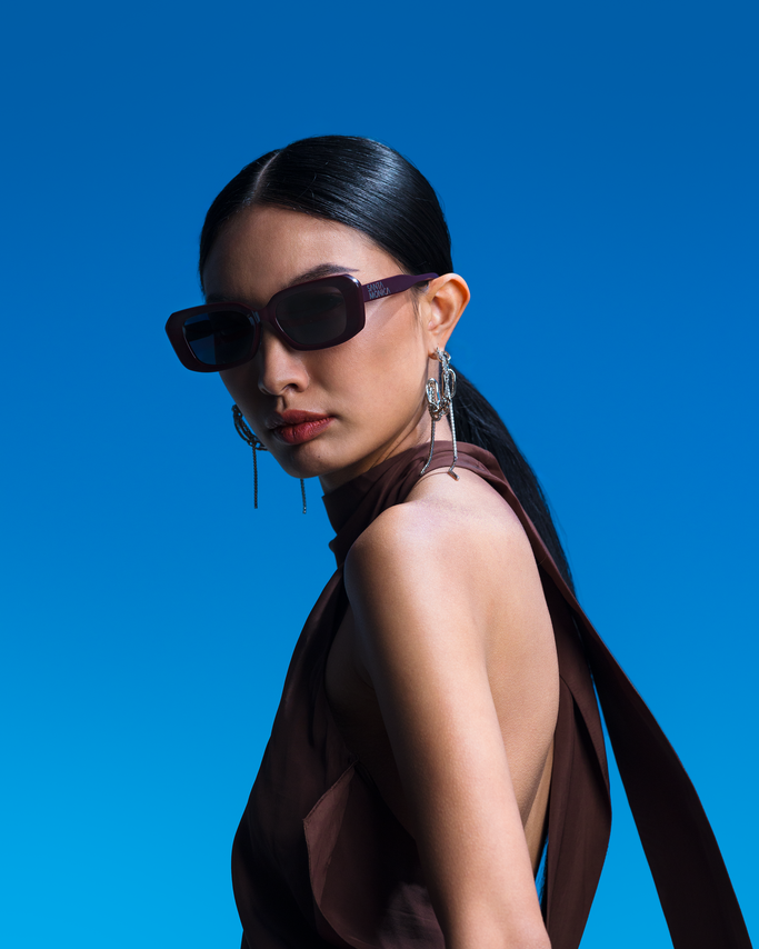 Woman wearing sunglasses and a brown dress against a blue background